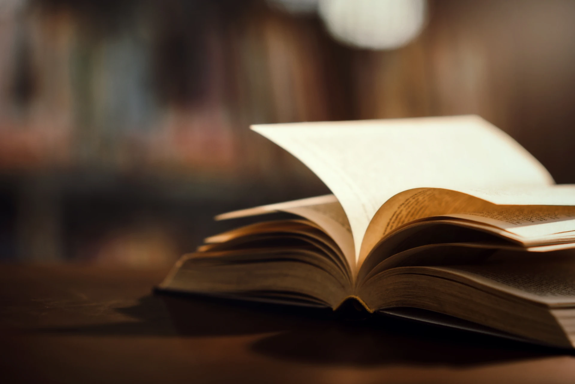 Imagem de um livro aberto sobre uma mesa, destacando suas páginas e textura. Ideal para amantes da leitura e educação.