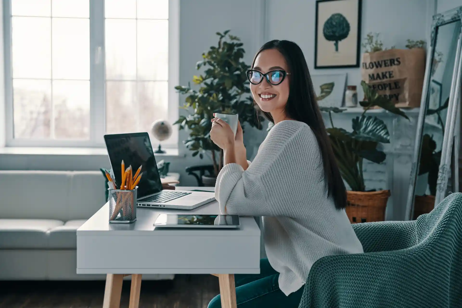 Mulher sorrindo e sentada em uma mesa de trabalho em sua casa trabalhando home office