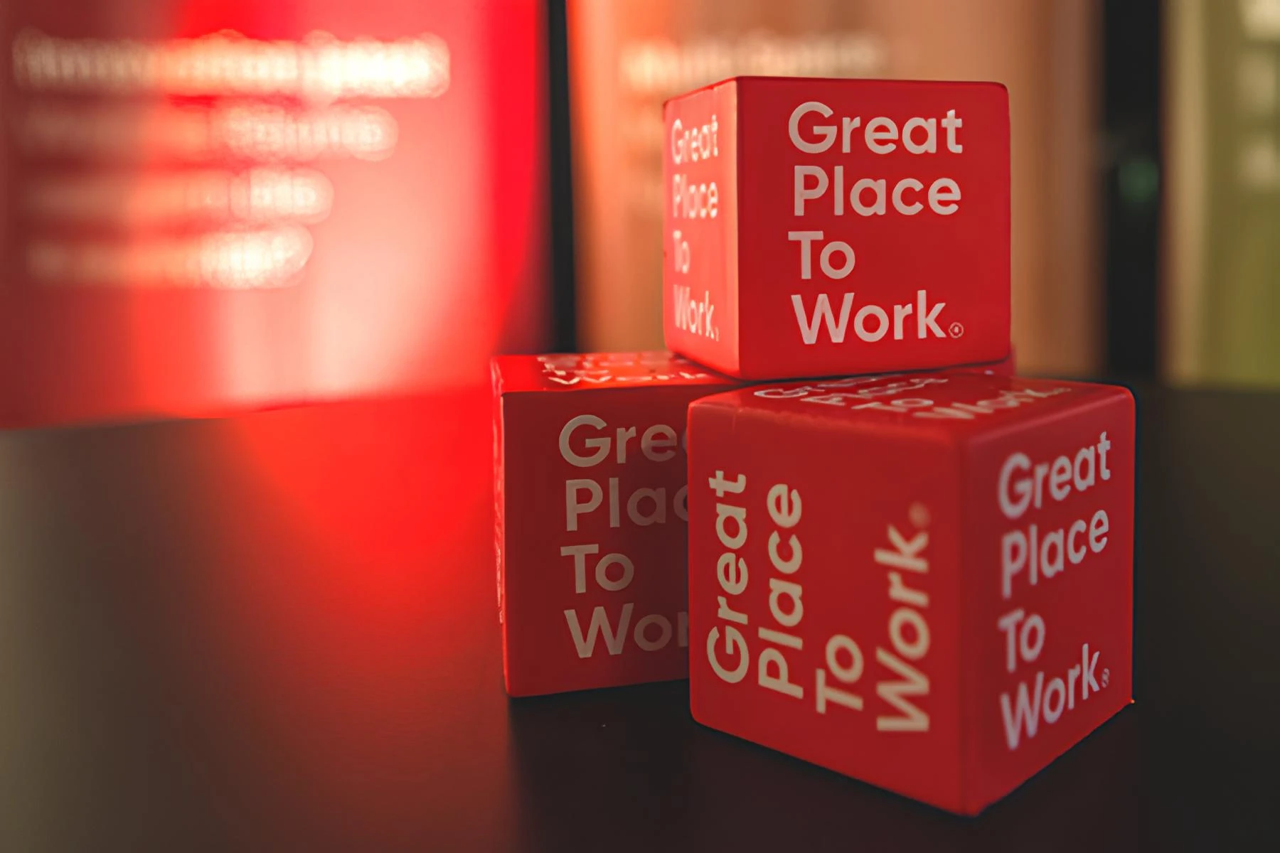 Imagem de blocos vermelhos com a frase 'Great Place To Work' impressa, simbolizando um ambiente de trabalho positivo e motivador.