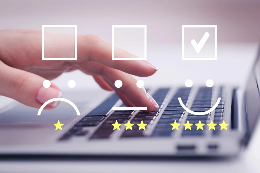 Imagem de uma mão digitando em um teclado, com ícones de feedback e estrelas, simbolizando avaliação e satisfação do usuário.