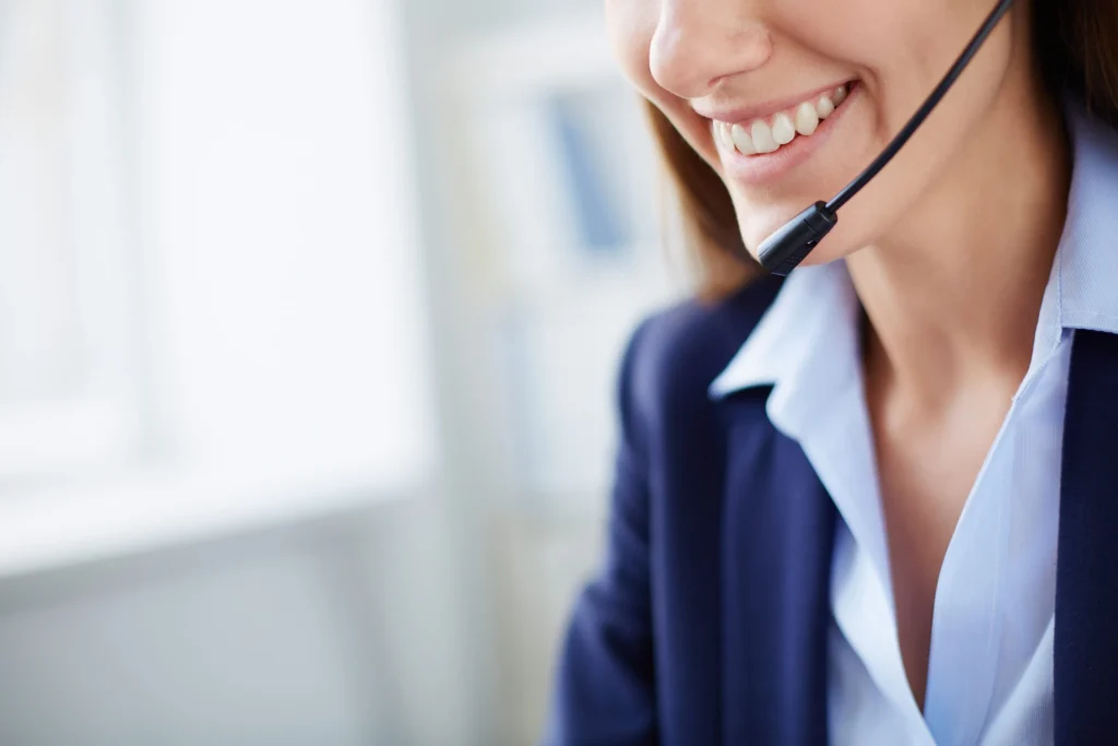 Mulher sorridente usando fone de ouvido em ambiente de trabalho, ideal para representação de atendimento ao cliente e comunicação.