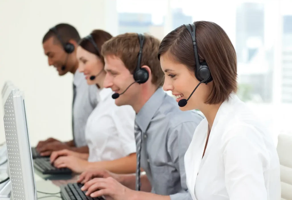 Equipe de call center concentrada em suas tarefas, utilizando headsets e computadores em um ambiente profissional.