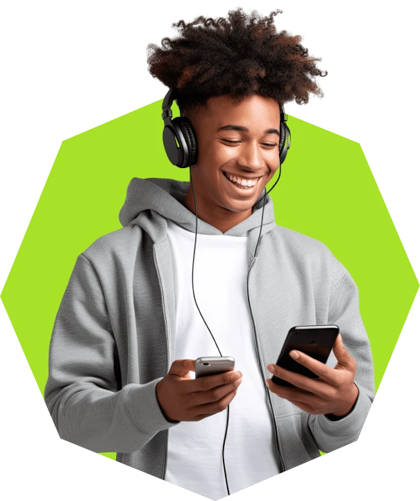 Jovem sorrindo usando fones de ouvido e segurando dois celulares, praticando multitarefa com tecnologia moderna, destacando tendência para jovens conectados.